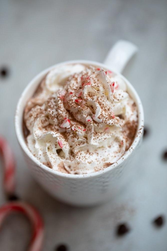 Heisse Schokolade Rezept Eine Tasse heißer Schokolade, gekrönt mit Schlagsahne und zerkleinerten Pfefferminzstangen.