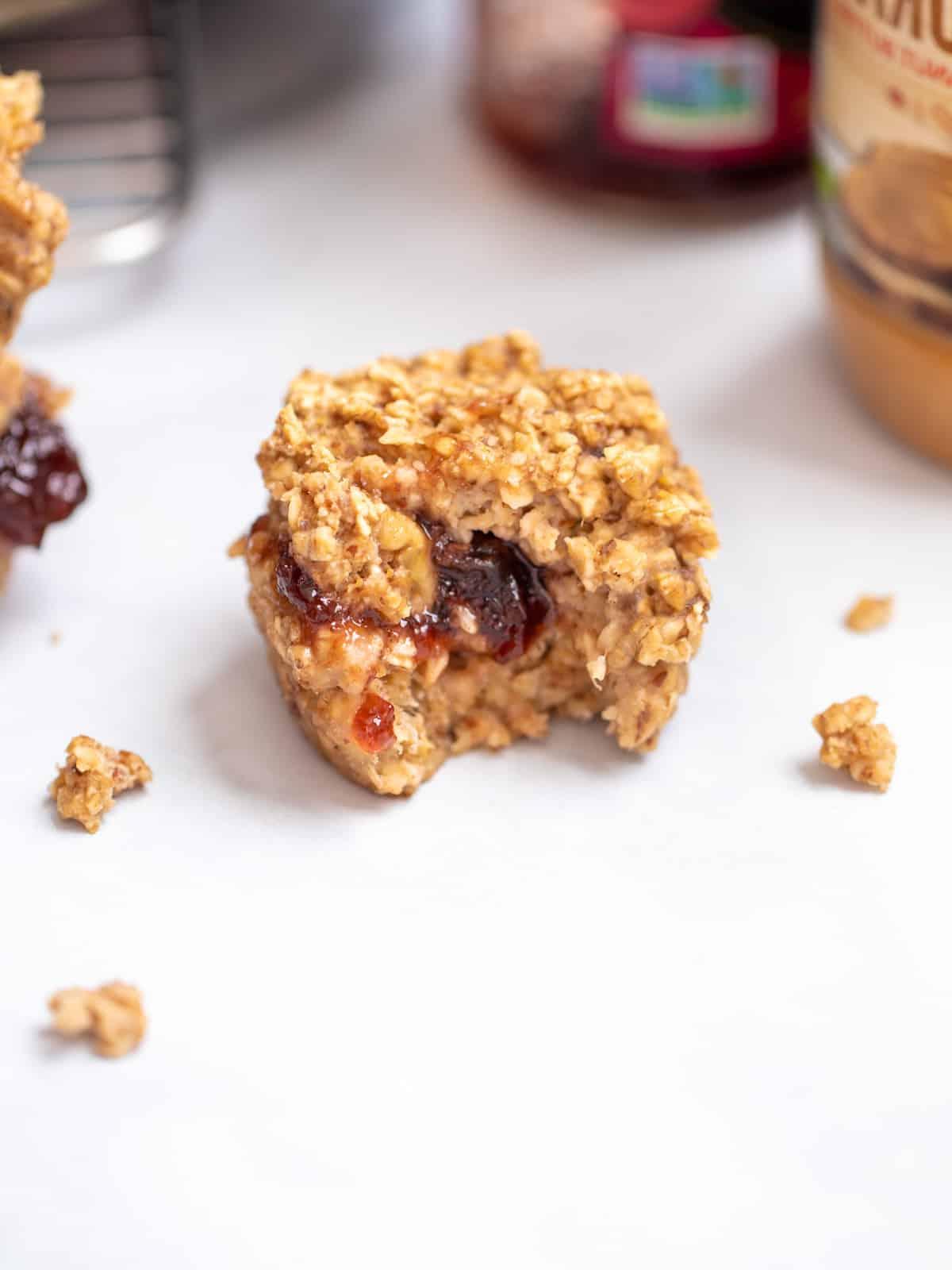 Haferflocken-Muffins für unterwegs Gebackener Haferflocken-Muffin, aus dessen Mitte Marmelade quillt.