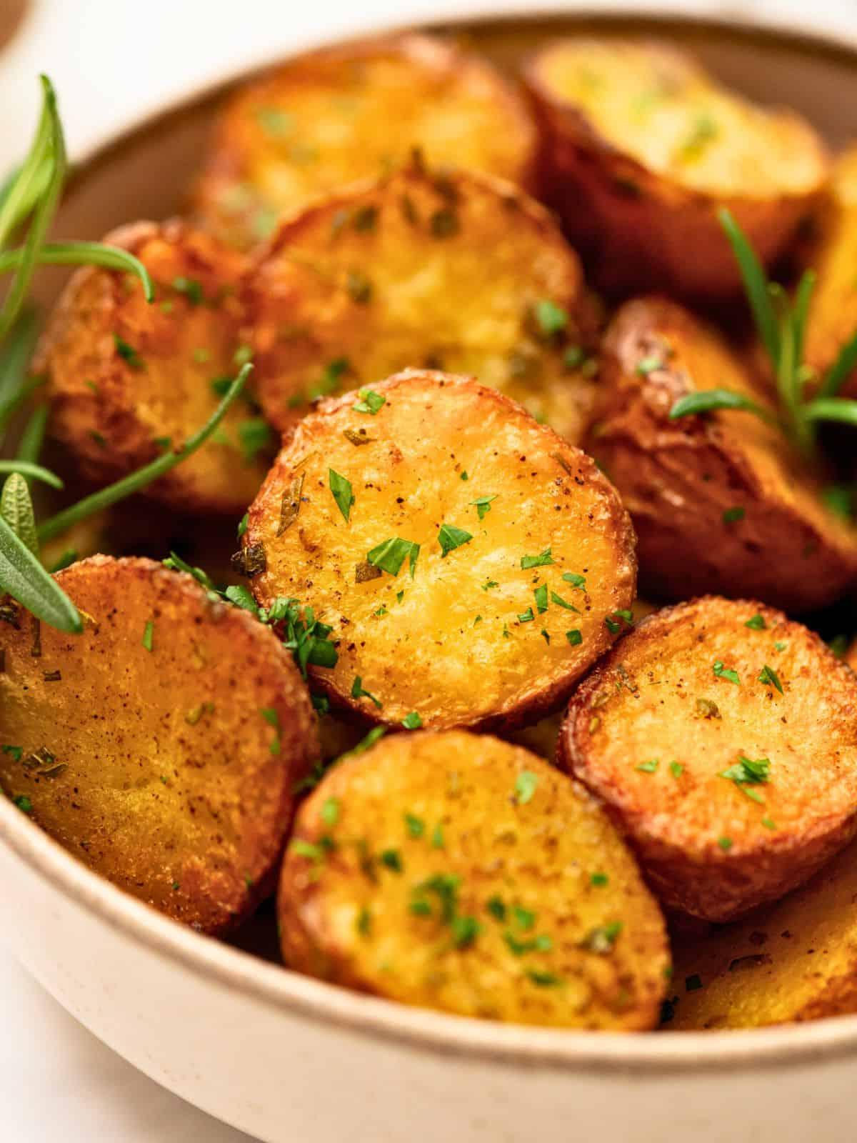 Geröstete Baby-Rotkartoffeln in einer Schüssel, gewürzt mit Knoblauchpulver, Salz, Pfeffer und Rosmarin.