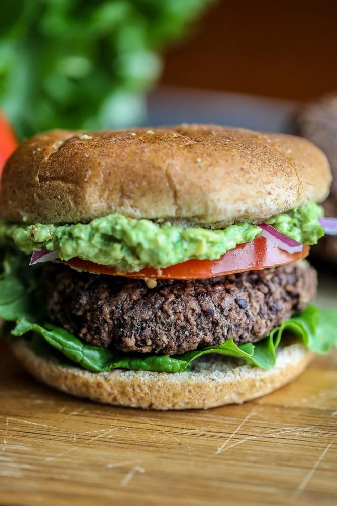 Schwarzer Bohnenburger mit Avocado auf Schneidebrett