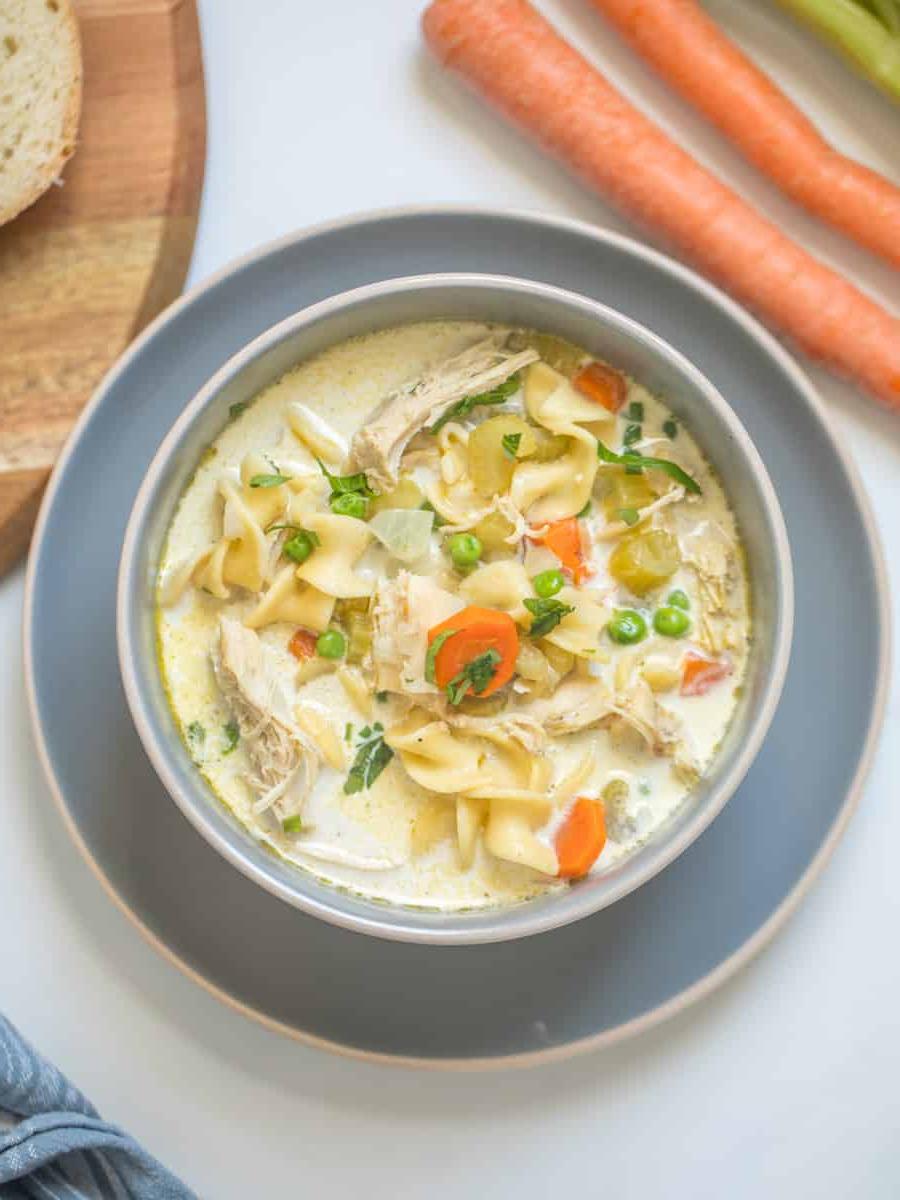 Frisch zubereitete cremige Instant Pot Puten-Nudelsuppe in einer Schale, garniert mit frischer Petersilie. Eine einladende, dampfende Mahlzeit, die zum sofortigen Genuss einlädt.