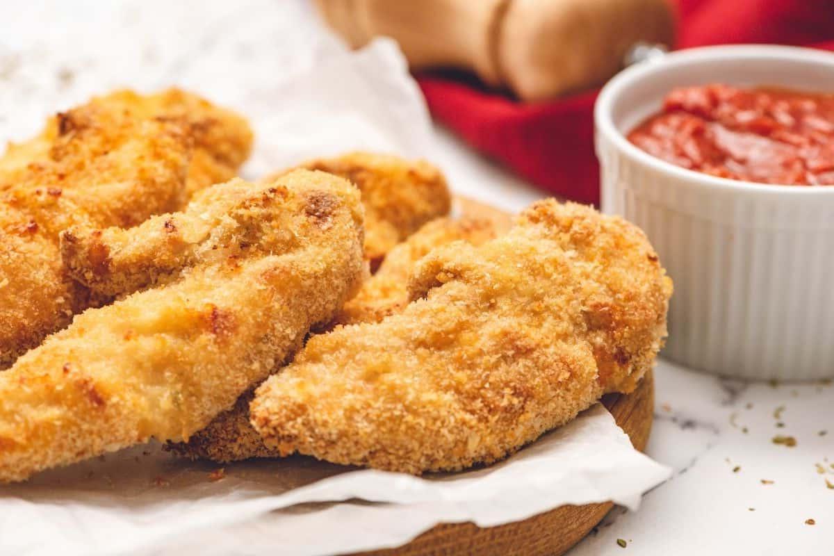 Chicken fingers on platter next to ketchup.