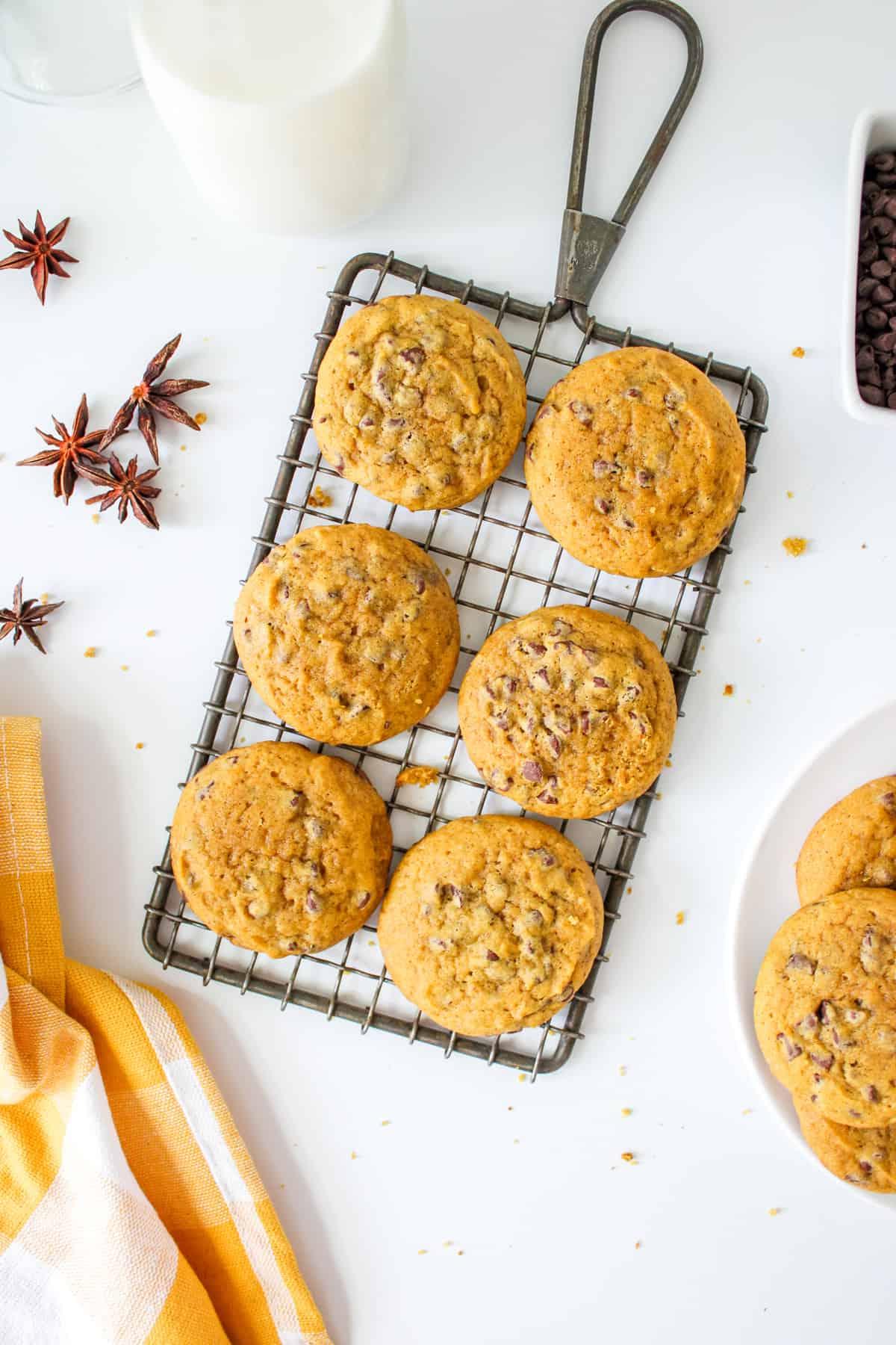 Kürbis-Schoko-Cookies mit Schokoladenstückchen – Ein herbstlicher Traum Abkühlende Kürbis-Schoko-Cookies auf einem Gitterrost mit einem Glas Milch im Hintergrund. Einladend und appetitlich angerichtet.