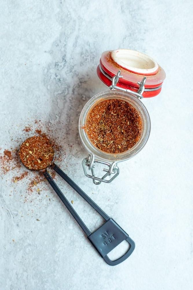 Würzglas mit selbstgemachtem Cajun-Gewürz neben einem Messlöffel.