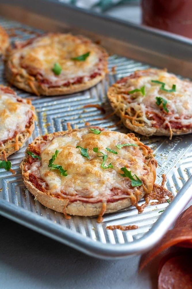 Ein Metallblech mit gebackenen English Muffin Pizzen mit geschmolzenem Käse.