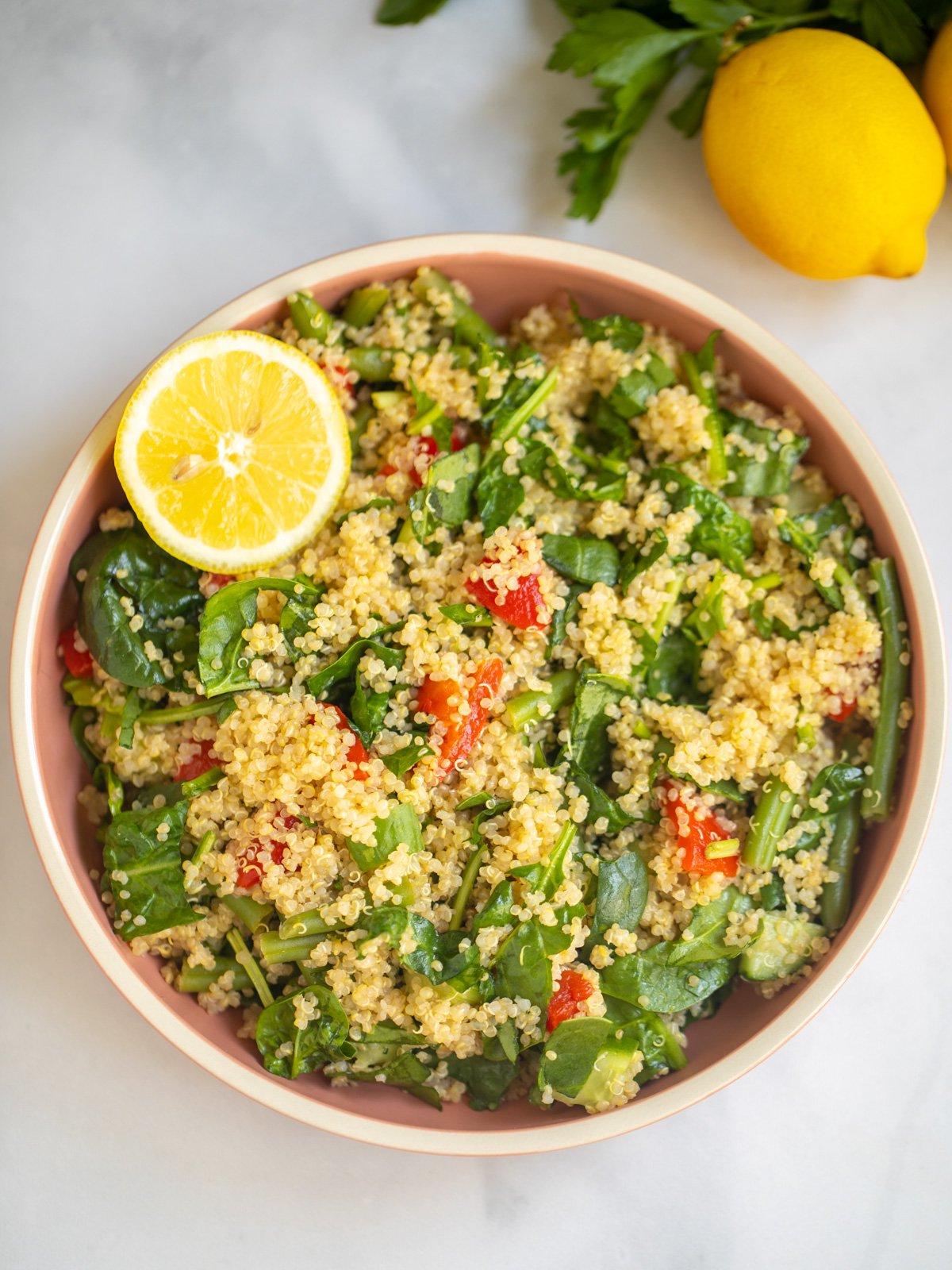 Schüssel Quinoa-Spinat-Salat mit frischer Zitrone im Hintergrund.