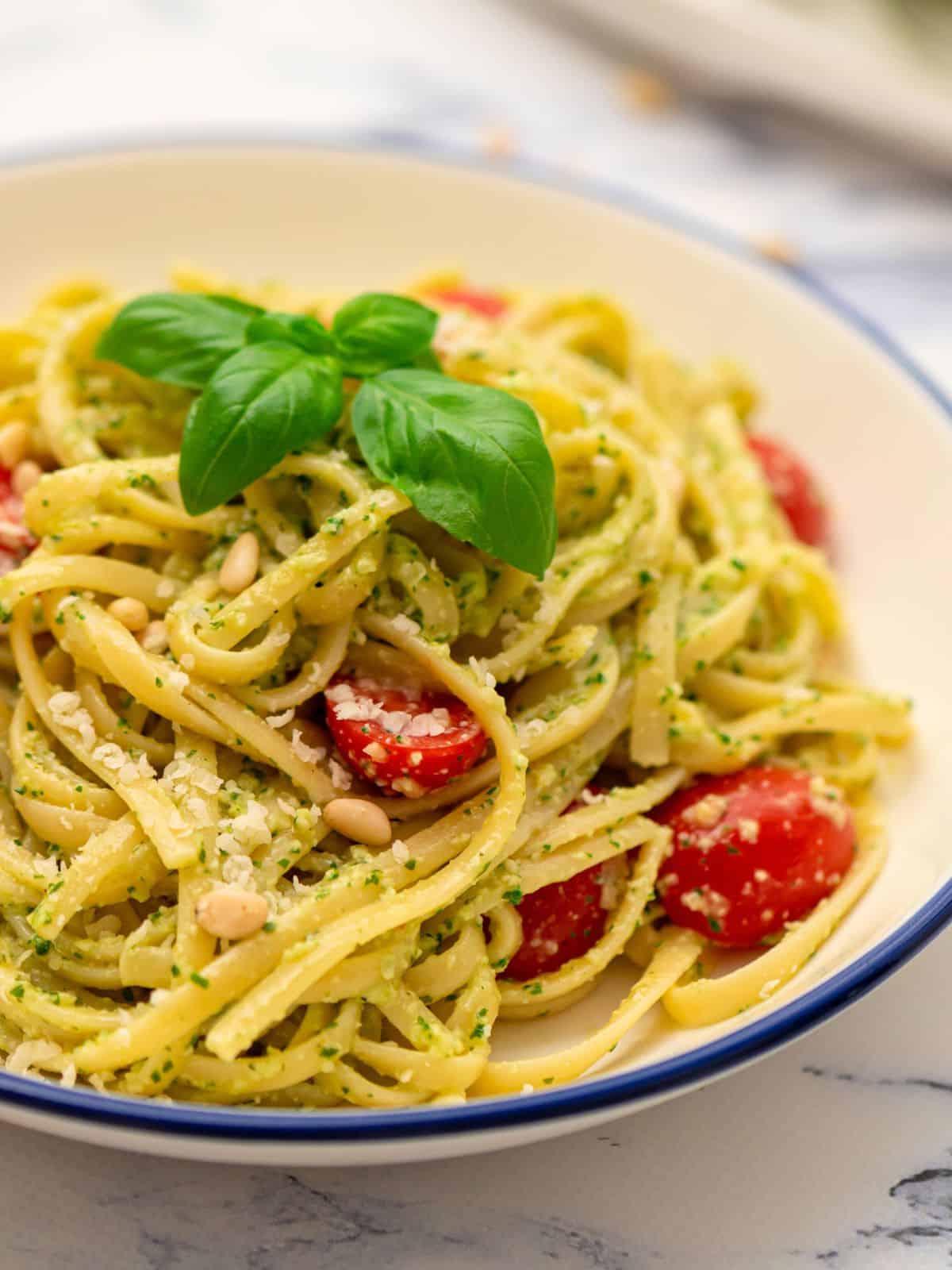 Eine Schüssel Pesto Nudeln mit frischen Tomaten und Basilikum garniert. Ein einfaches und farbenfrohes Gericht.