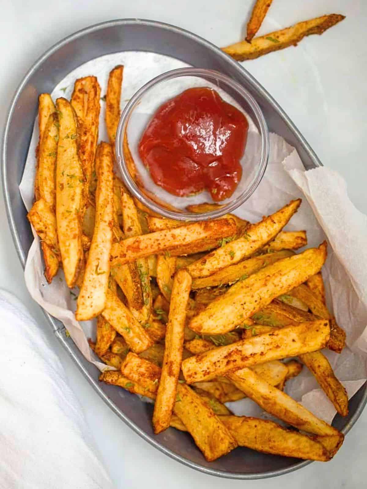 Ein Korb voller selbstgemachter Pommes aus der Heißluftfritteuse, serviert mit Ketchup.
