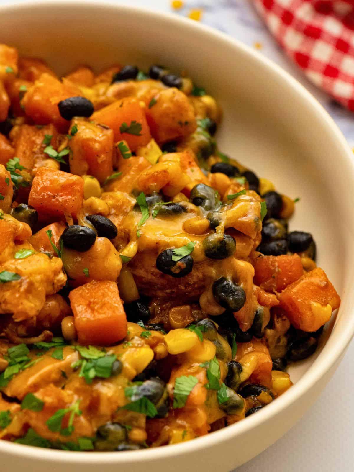 Große Schüssel mit käsiger Hähnchen-Süßkartoffel-Pfanne mit Bohnen und Mais.