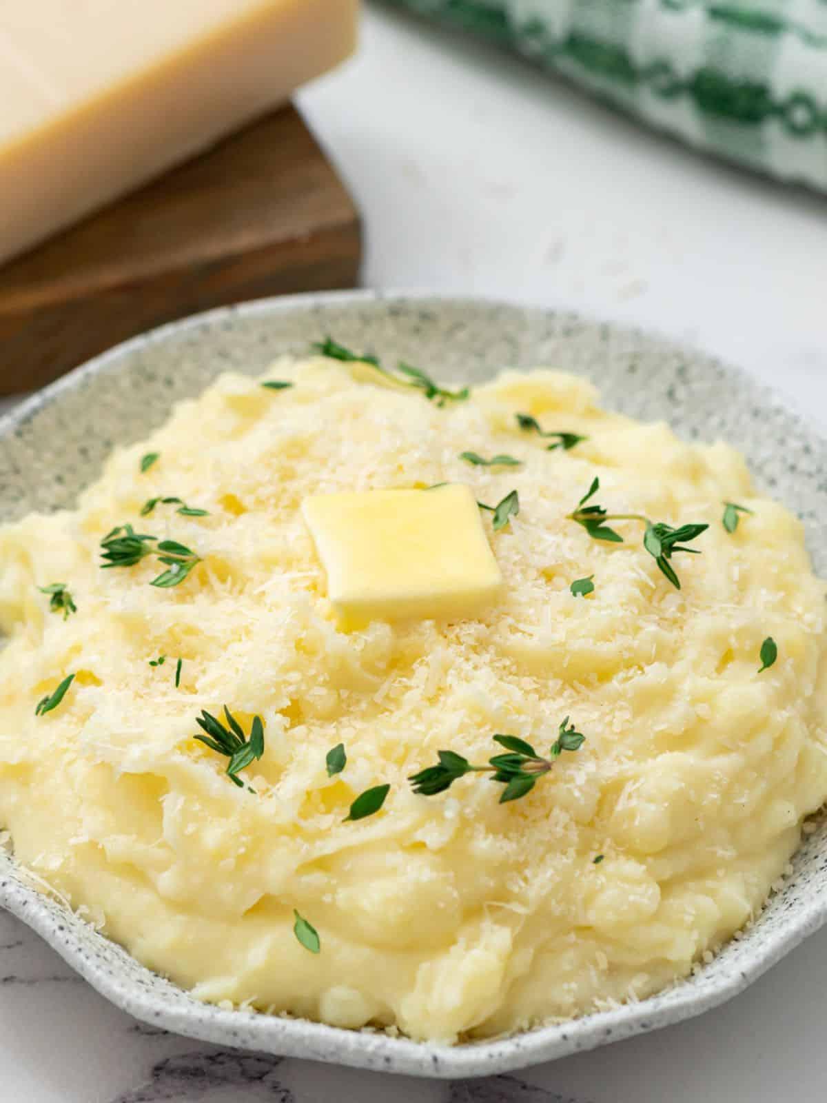 Servierfertiges Kartoffelpüree aus dem Slow Cooker, garniert mit Parmesan, Butter und Thymian.