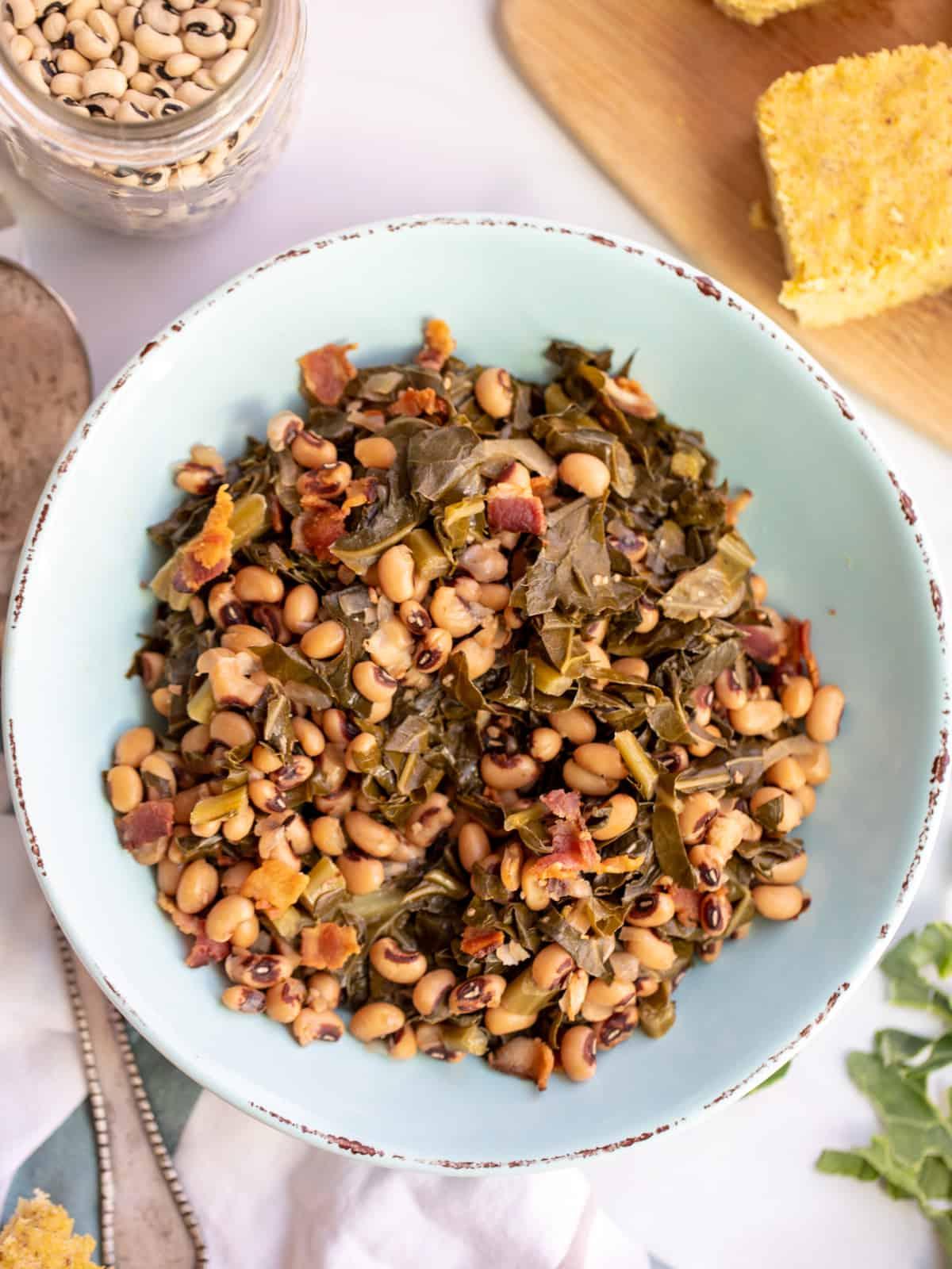 Instant Pot Augenbohnen und Blattkohl Schale mit Instant Pot Augenbohnen und Blattkohl neben Maisbrot und getrockneten Bohnen.