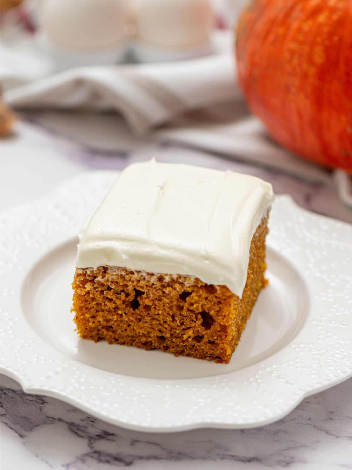 Kürbiskuchen Ein Stück Kürbiskuchen mit Frischkäse-Frosting auf einem weißen Teller.