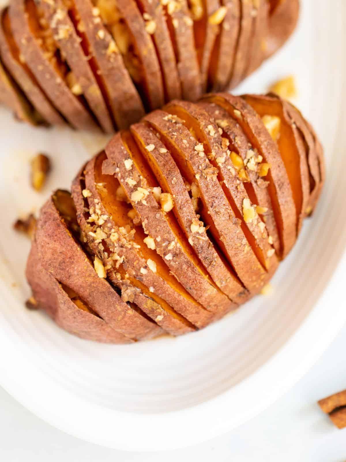 Hasselback Süßkartoffeln mit Ahorn-Glasur Draufsicht auf eine Ahorn-glasierte Hasselback-Süßkartoffel auf einer weißen Platte.
