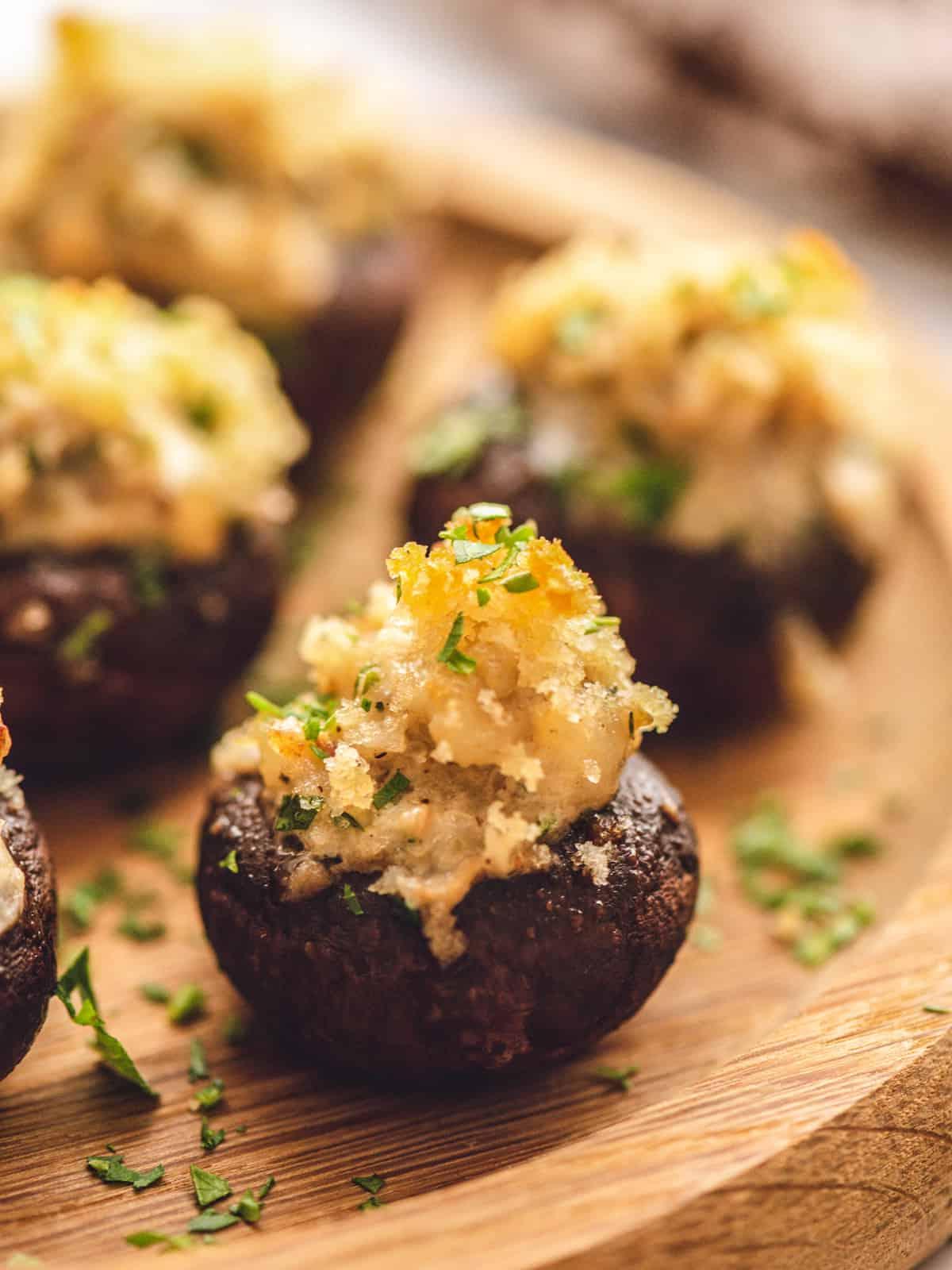 Gefüllte Champignons mit Wurst Nahaufnahme eines gefüllten Champignons auf einer Holzplatte.