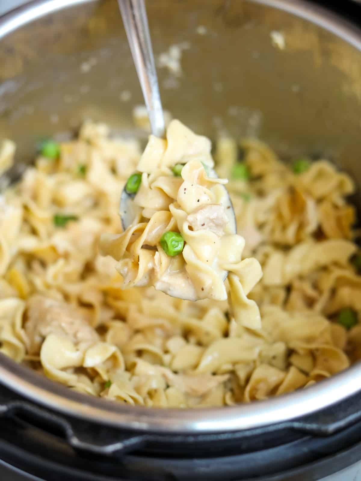 Löffel kommt aus dem Instant Pot mit Nudeln, Thunfisch und Erbsen.