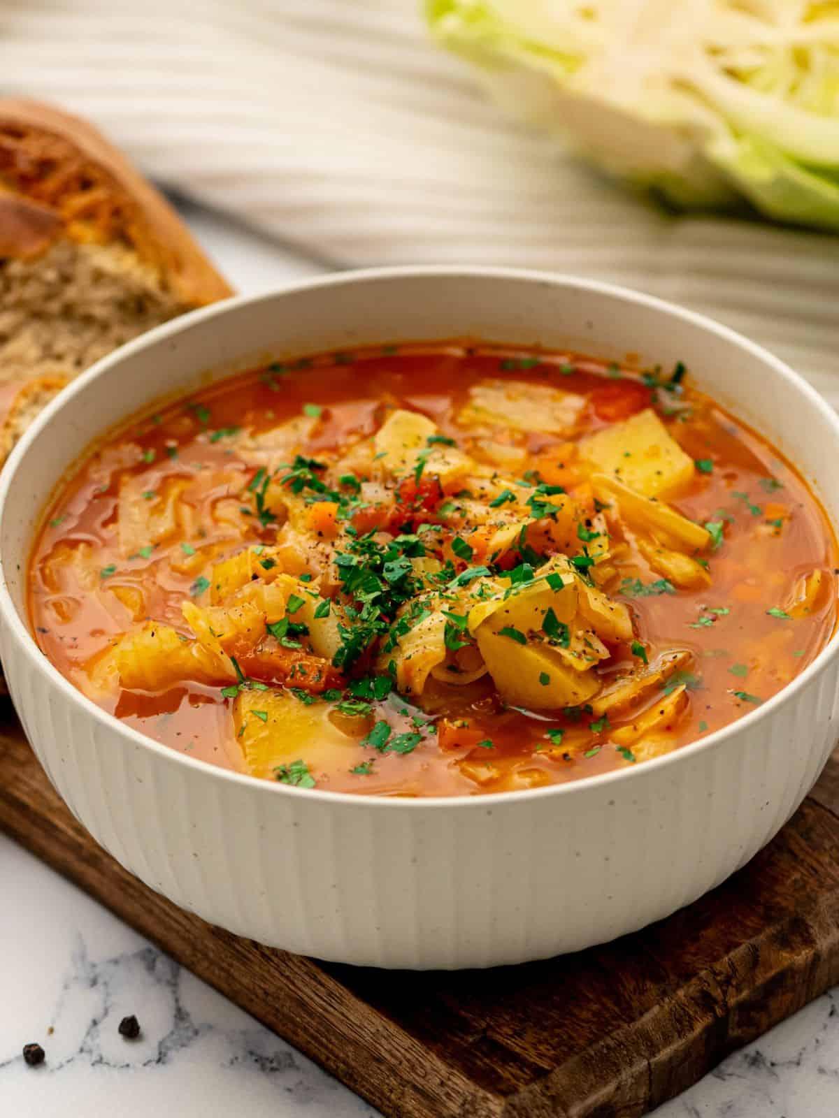 Instant Pot Kohlsuppe Rezept Instant Pot Kohlsuppe in einer Schüssel neben herzhaften Brötchen.