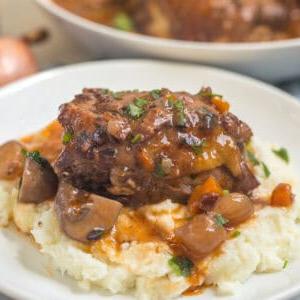 Instant Pot Coq au Vin Hähnchenkeule mit reichhaltiger Pilz-Rotwein-Soße über Kartoffelpüree serviert.