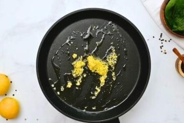 Leicht gerösteter Knoblauch in nativem Olivenöl extra in einer großen Bratpfanne.