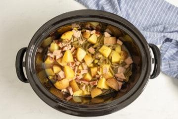 Slow Cooker mit Schinken, grünen Bohnen und Kartoffeln im Inneren.