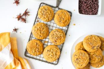 Kürbis-Schoko-Cookies auf einem Abkühlgitter mit einem Glas Milch im Hintergrund, bereit zum Genießen.
