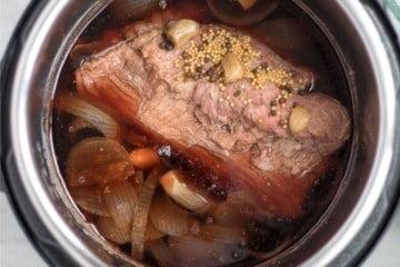 Gekochtes Corned Beef im Innentopf mit Zwiebeln und Knoblauch.