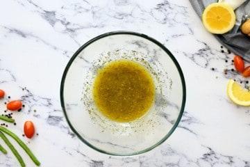 Hausgemachtes italienisches Dressing in einer durchsichtigen Schüssel nach dem Verquirlen.