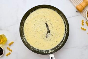 Cremige Soße für Cavatappi Pasta in einer Pfanne, zubereitet mit Schlagsahne und Parmesan.