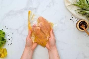 Hähnchenbrüste in einem großen Gefrierbeutel mit Orangen-Dressing.