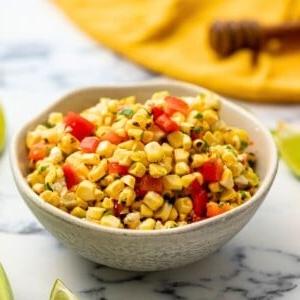 Maissalsa in Schale mit Limetten im Hintergrund.