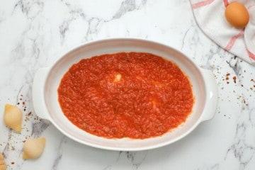 Spaghettisauce dünn auf einer ovalen Auflaufform verteilt.