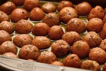 Gewürzte rote Baby-Kartoffeln mit der Schnittfläche nach unten auf dem Backblech.