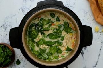 Instant Pot gefüllt mit cremiger Hähnchen-Gnocchi-Suppe, garniert mit frischem Spinat.