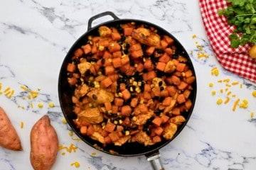 Pfanne mit Süßkartoffeln, Hähnchen, Mais und schwarzen Bohnen vermischt.