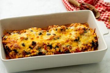Gebackenes Cowboy Hähnchen mit Bohnen, Mexiko-Mais und Käse in einer weißen Auflaufform.