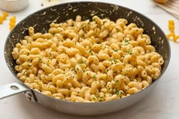 Cavatappi-Nudeln mit Parmesan-Sahne-Soße und gehackter Petersilie in einer Pfanne.