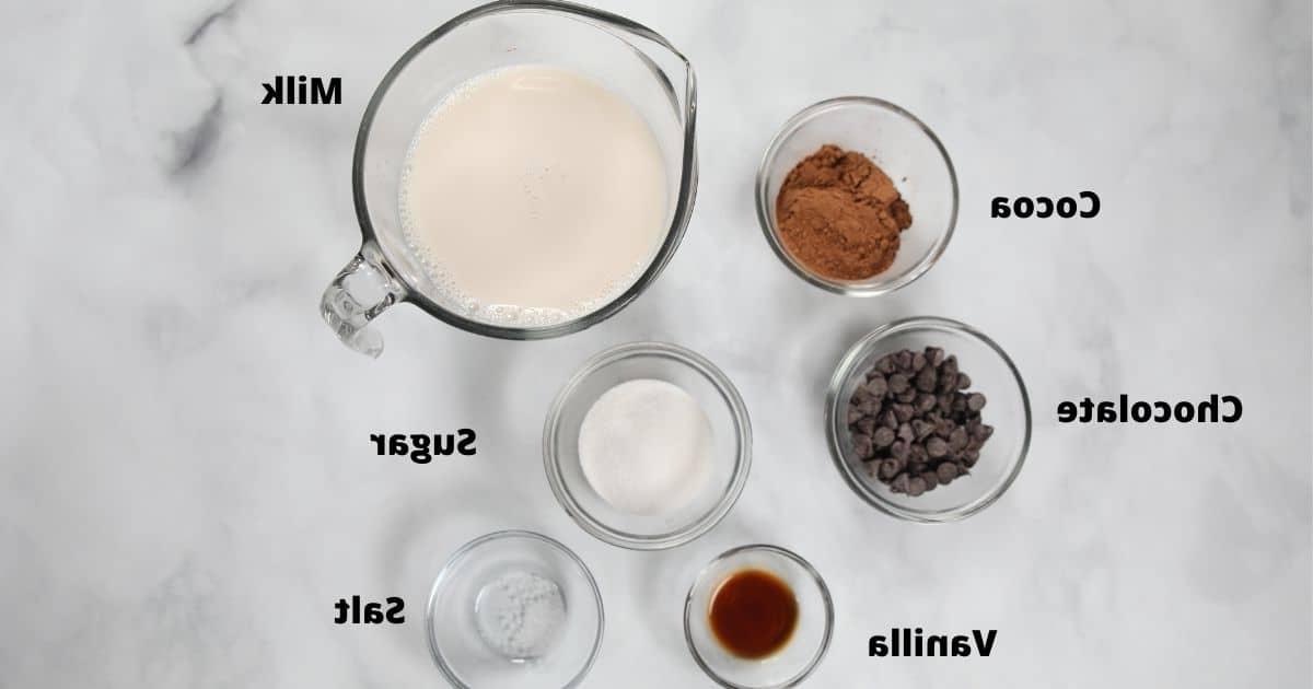 Rezept für Heiße Schokolade Zutaten für Heiße Schokolade auf weißer Theke, beschriftet.