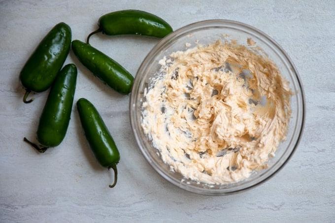 Frischkäsefüllung für gefüllte Jalapeños neben frischen Jalapeños.