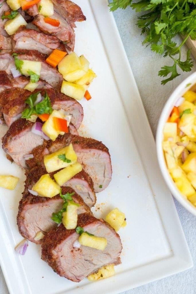 Gegrilltes Schweinefilet in Scheiben geschnitten und mit Ananas-Salsa belegt
