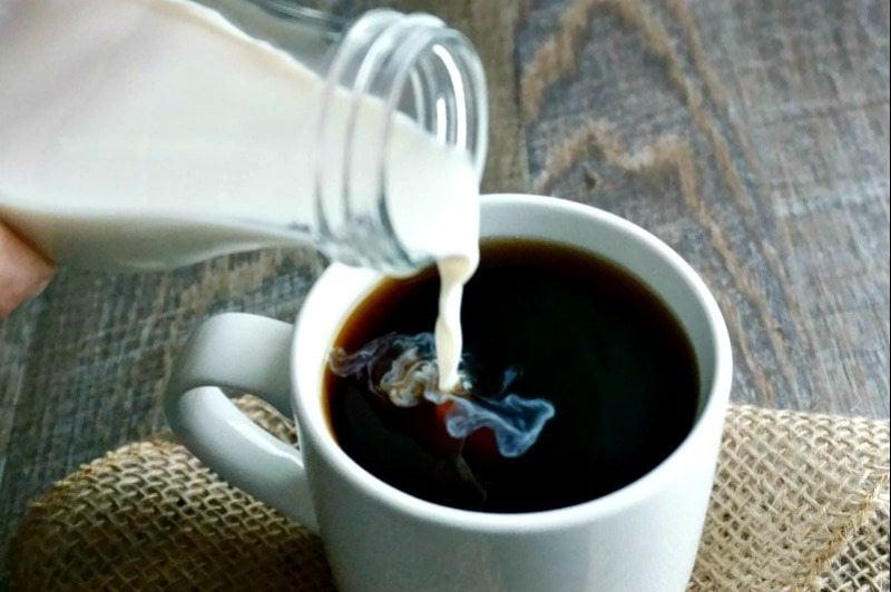 Vanille-Kokos-Kaffeeweißer wird in dunklen Kaffee gegossen.