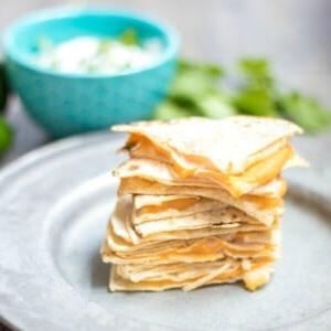 Gesündere Käse-Quesadilla 2 Kürbis- und Käse-Quesadilla in Spalten geschnitten auf silbernem Teller