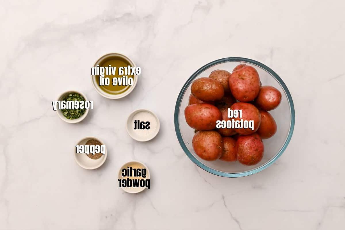 Foto zeigt rote Baby-Kartoffeln, natives Olivenöl extra, Salz, Pfeffer, Knoblauchpulver und Rosmarin.