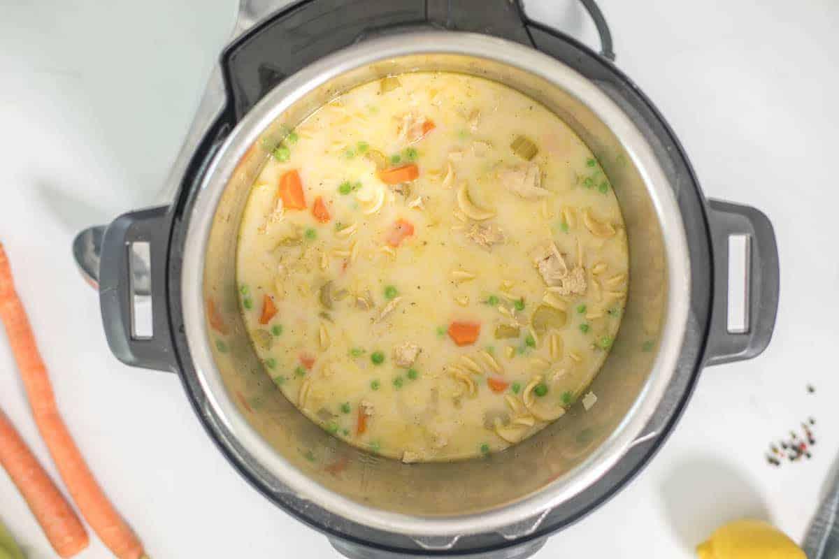 Cremige Puten-Nudelsuppe im Innenbehälter des Instant Pots, mit Karotten- und Selleriestücken, bereit zum Servieren.
