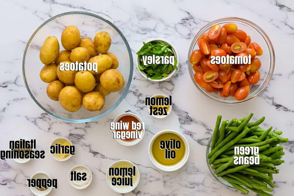 Rezept Mayonnaisefreier Kartoffelsalat Zutaten für italienischen Kartoffelsalat, auf der Theke angeordnet und beschriftet.