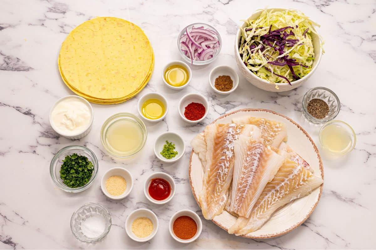 Zutaten für Fisch Tacos und Fisch Taco Toppings auf der Arbeitsplatte.