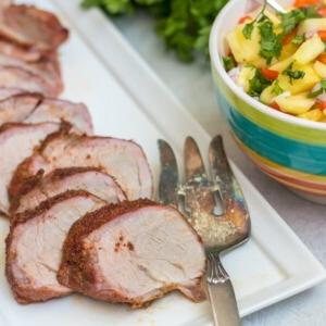 Gegrilltes Schweinefilet auf einer weißen Platte neben Ananas-Salsa