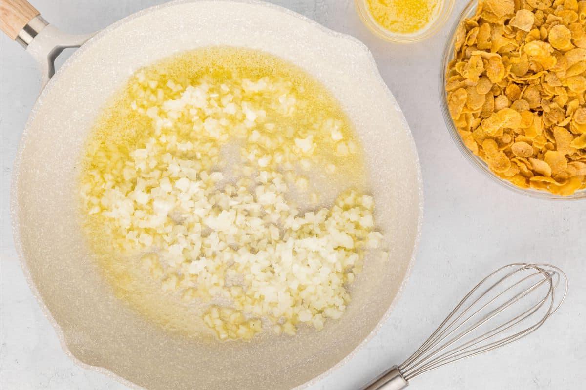 Hash-Brown-Kartoffelauflauf mit Cornflakes Pfanne mit geschmolzener Butter und gehackten Zwiebeln.