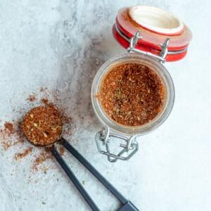 Glas mit selbstgemachtem Cajun-Gewürz neben einem Messlöffel