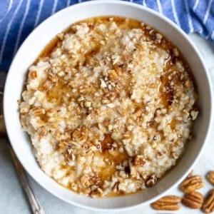 Schüssel mit Slow Cooker Haferbrei, garniert mit Ahornsirup und Nüssen