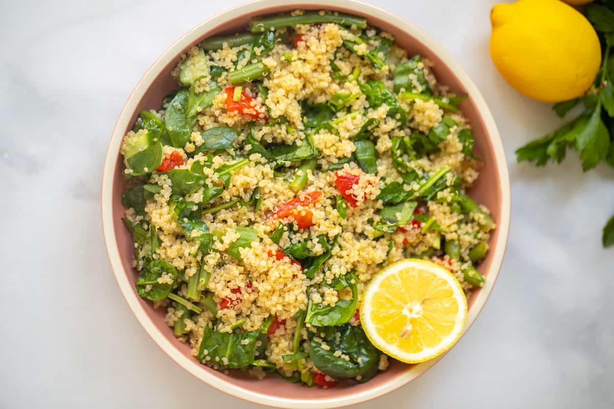 Schüssel Quinoa-Salat mit Spinat, gerösteten roten Paprika und Zitrone.