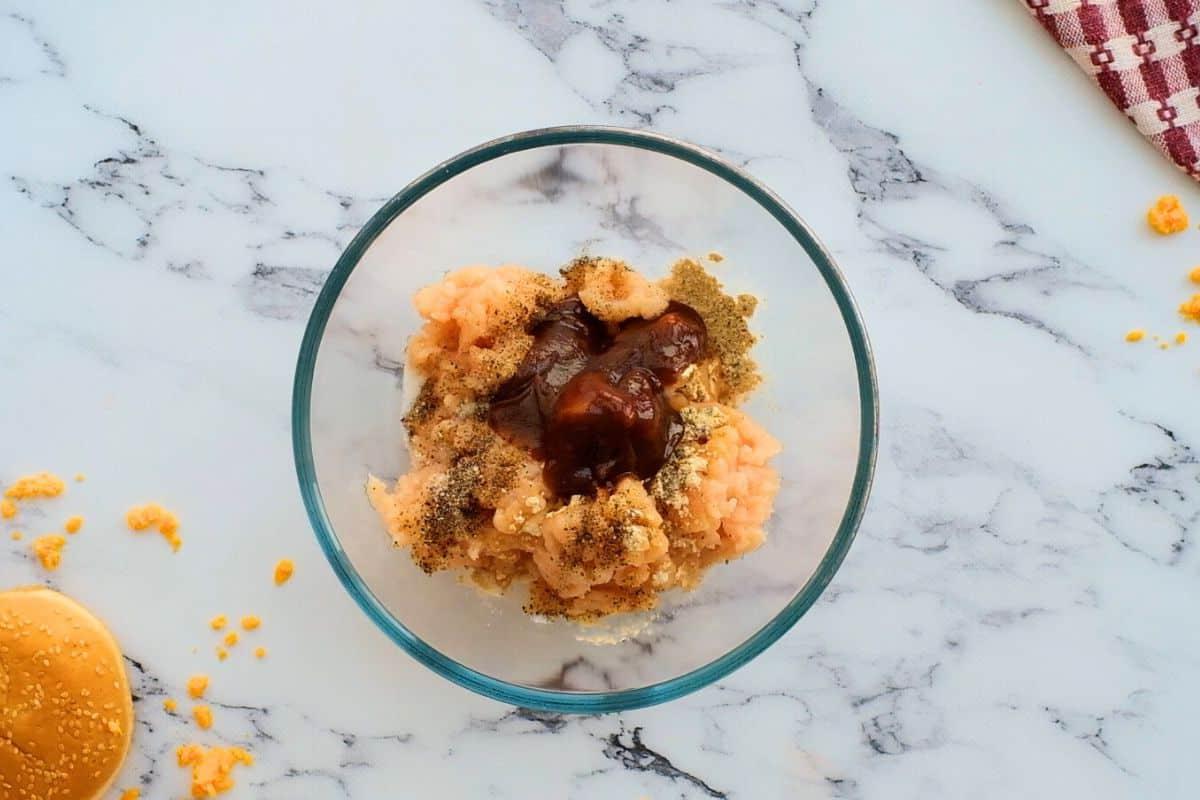 Raw chicken in mixing bowl with seasonings.